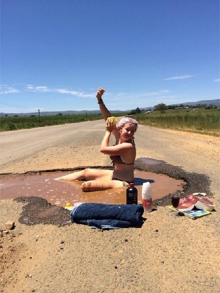 ビキニの女性が陥没穴の泥水で入浴して道路補修を訴える。画像は、Lydenrust Guest FarmのFacebookのスクリーンショット。