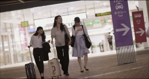 女性3人がスーツケースを手に旅行へ