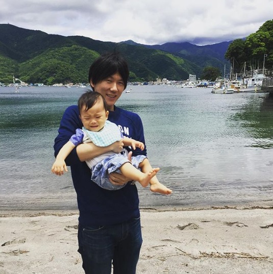 甥を抱く古市憲寿氏（画像は『古市憲寿　2016年6月3日付Instagram「昔、家族で行った場所に。すぐに泣かれるの巻。」』のスクリーンショット）