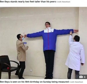 ギネス世界記録のスタッフに測定される小宇君（画像は『The Sun　2020年10月20日付「NEW HEIGHTS This is the 14-year-old Chinese boy who measures well over 7 feet tall and is set to become the tallest male teenager」（Credit: Newsflash）』のスクリーンショット）