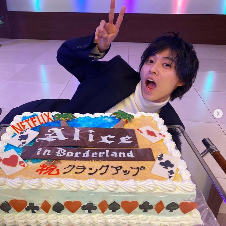 『今際の国のアリス』クランクアップ記念ケーキの横でおどける山崎賢人（画像は『桜田 通 Dori Sakurada　2020年12月12日付Instagram「賢人がインスタでバースデーイベントにサプライズゲストで来てくれた時の写真を載せてくれたので、お返しに『今際の国のアリス』の打ち上げの時のクランクアップ記念ケーキとの写真を載せます」』のスクリーンショット）
