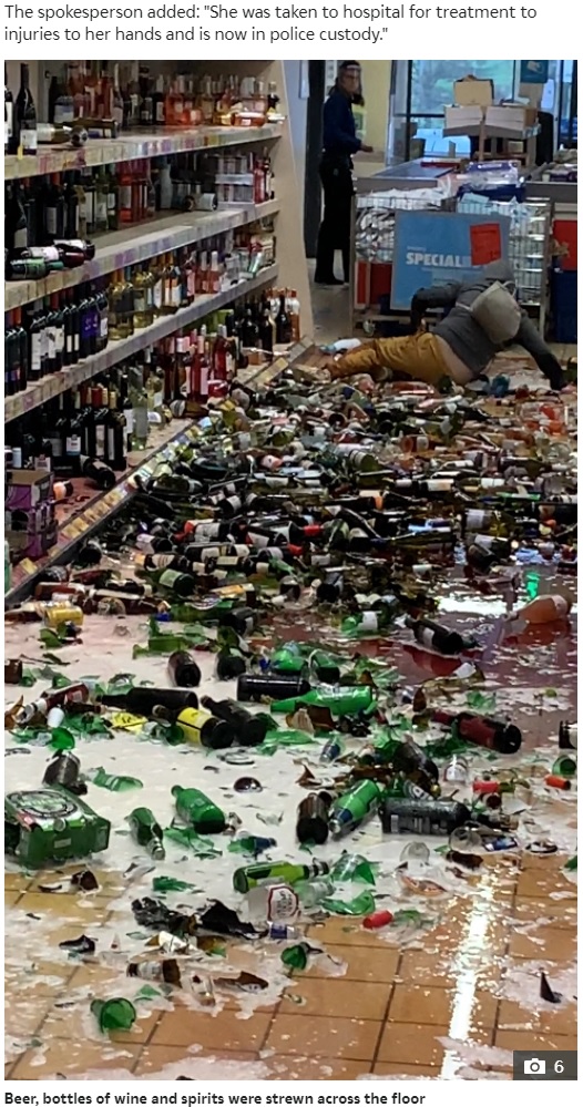 女はアルコールまみれになった床で転倒も（画像は『The Sun　2020年11月26日付「GETTING SMASHED Bizarre moment shopper chucks 500 booze bottles on floor in five-minute Aldi wrecking rampage」』のスクリーンショット）