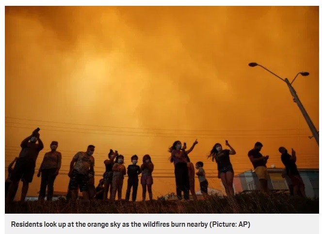 オレンジ色に染まった空を見上げる人々（画像は『Metro　2021年1月16日付「Skies turn red over Chile as ‘deliberate’ wildfires tear through people’s homes」（Picture: AP）』のスクリーンショット）