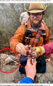 4人目はカモフラージュ柄のジャケットを着用していた（画像は『The Scottish Sun　2021年2月17日付「THREE CHEERS OR FOUR? Can you spot the fourth person in this outdoor whisky optical illusion?」（Credit: Reddit）』のスクリーンショット）