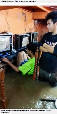 濁った水が流れ込んだ店内（画像は『Metro　2021年7月27日付「Hardcore gamers carry on playing as room floods during typhoon」（Picture: ViralPress）』のスクリーンショット）