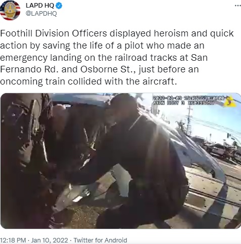 パイロットを引っ張り出す警察官（画像は『LAPD HQ　2022年1月10日付Twitter「Foothill Division Officers displayed heroism and quick action by saving the life of a pilot who made an emergency landing on the railroad tracks at San Fernando Rd.」』のスクリーンショット）