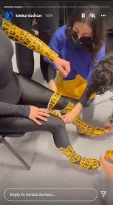 キムの手脚に粘着テープを巻くスタッフ達（画像は『Kim Kardashian　2022年3月6日付Instagram』のスクリーンショット）