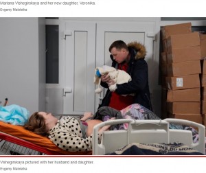 ベロニカちゃんを抱く夫を見つめるマリアナさん（画像は『New York Post　2022年3月11日付「Pregnant Ukrainian blogger seen fleeing maternity hospital blast has given birth」（Evgeniy Maloletka）』のスクリーンショット）