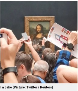 スタッフがケーキを拭き取る光景をカメラに収める人々（画像は『Metro　2022年5月30日付「Mona Lisa attacked with cake by man wearing disguise to look like an old woman」（Picture: Twitter / Reuters）』のスクリーンショット）