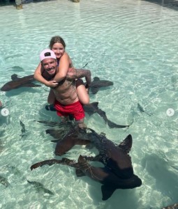 小型サメのいる水中でおんぶしているデヴィッドとハーパーちゃん（画像は『Victoria Beckham　2022年5月2日付Instagram「Happy birthday ＠davidbeckham the best daddy!!!」』のスクリーンショット）
