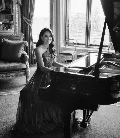 ウィンザー城のクリムゾン・ドローイング・ルームでピアノの前に座るキャサリン皇太子妃。「ジェニー・パッカム」のロングドレスを着て、ピアノの腕前を披露した（画像は『The Prince and Princess of Wales　2023年5月14日付Instagram「A little sneak peek behind the scenes at the filming for last night’s ＠Eurovision surprise」』のスクリーンショット）