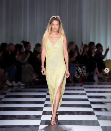 「ヴェルサーチェ」のランウェイを歩くジジ・ハディッド。深いスリットの入ったイエローのロングドレスを纏っていた（画像は『Donatella Versace　2023年9月23日付Instagram「Fresh and graphic.」』のスクリーンショット）
