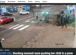 事故直後、人々が現場に集まって来た。車が横転した背後には娘を抱っこする母親の姿が見える。親子も運転手も奇跡的に大事に至らなかった（画像は『The Sun 　2023年12月19日付「CLOSE CALL Shocking moment mum pushing her child in a pram narrowly escapes devastation as car flips and crashes in her path」』のスクリーンショット）