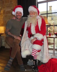 サンタと肩を抱き合うデヴィッド・ベッカム。大きな笑みを見せている（画像は『Victoria Beckham　2023年12月24日付Instagram「When Santa comes to visit!!!」』のスクリーンショット）