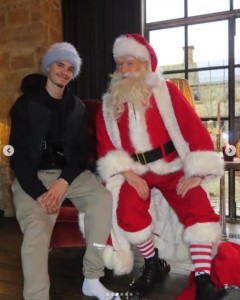 ベッカム家の次男ロメオとサンタ。ロメオは温かそうなブルーの帽子を被っていた（画像は『Victoria Beckham　2023年12月24日付Instagram「When Santa comes to visit!!!」』のスクリーンショット）
