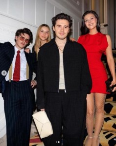 ブルックリンの妻ニコラは真っ赤なミニドレスを着て出席。後部にはクルスとハーパーちゃんが立っている（『Victoria Beckham　Instagram「Always there to support me」』より）